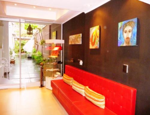 a red bench in a room with paintings on the wall at Bohemia Hotel Boutique in Mendoza