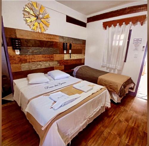 a bedroom with two beds and a clock on the wall at Pouso das Gerais in Tiradentes