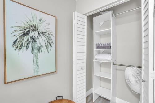 um armário branco com uma impressão de palma na parede em Relax Poolside & Walk or Bike to the Beach From This Amazing Naples Pool Home! em Naples