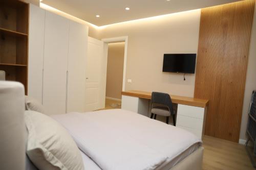a bedroom with a bed and a desk with a television at J&D Rooms Korce in Korçë