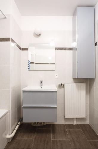 une salle de bain blanche avec un lavabo et un miroir dans l'établissement Sérénité et Tranquillité à Proximité de Paris, à Argenteuil