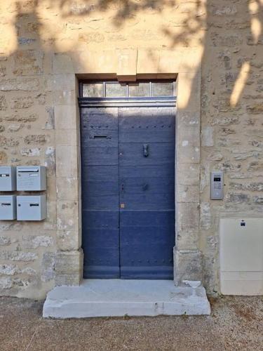 une porte de garage bleue dans un bâtiment en pierre dans l'établissement Appartement centre-ville avec cour privative, à Malaucène