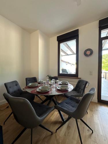 uma sala de jantar com uma mesa e quatro cadeiras em LiT LiVING: Luxury - Box Spring - große Terrasse - bbq - sagenhafte Aussicht em Weinheim