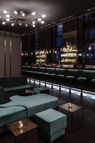 a bar with green couches and a bar with lights at Hotel AMANO Grand Central in Berlin
