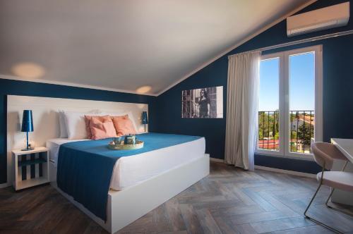 Dormitorio azul y blanco con cama y ventana en Vinkuran Residence - Adults Only en Pula