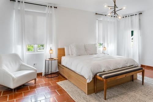 Un dormitorio blanco con una cama y una silla. en Daria Beachfront community steps 2 pool- Generator, en Sabana