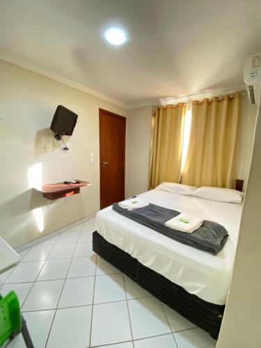 um quarto de hotel com uma cama e uma televisão em Buriti Hotel - Barra do Riacho, Aracruz ES em Aracruz