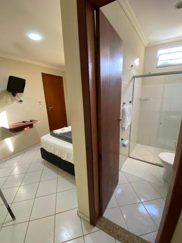 a bathroom with a toilet and a shower and a bed at Buriti Hotel - Barra do Riacho, Aracruz ES in Aracruz
