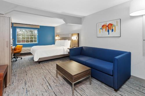 a hotel room with a bed and a blue couch at Holiday Inn Express & Suites Carmel North – Westfield, an IHG Hotel in Carmel