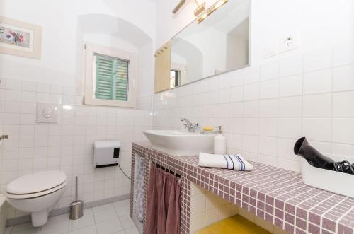 a white bathroom with a sink and a toilet at Apartment City Center in Jelsa
