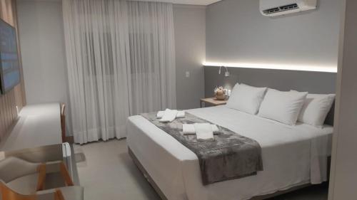 a bedroom with a large white bed and a chair at Hotel San Marinho in União da Vitória