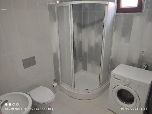 y baño con ducha y lavadora. en Espinaz Apart Otel, en Bostaniçi