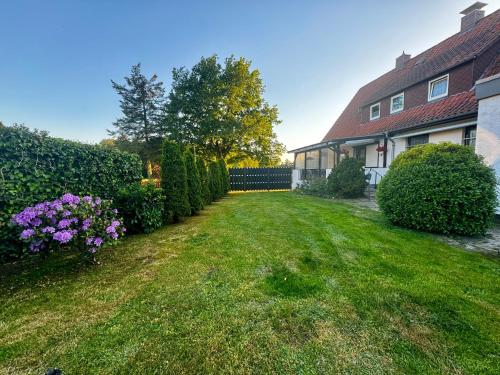 un patio con una casa y algunos arbustos y flores en Ferienwohnung E, en Soltau