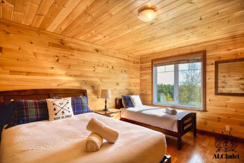 1 dormitorio con 2 camas en una cabaña de madera en Domaine du Hameau en Petite-Rivière-Saint-François