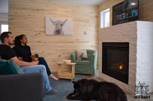 eine Gruppe von Menschen sitzt in einem Wohnzimmer mit Kamin in der Unterkunft Le Loonix- Chalet familiale avec Spa in Petite-Rivière-Saint-François