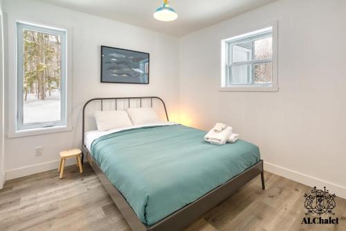 1 dormitorio con 1 cama y 2 ventanas en Le Loonix- Chalet familiale avec Spa en Petite-Rivière-Saint-François