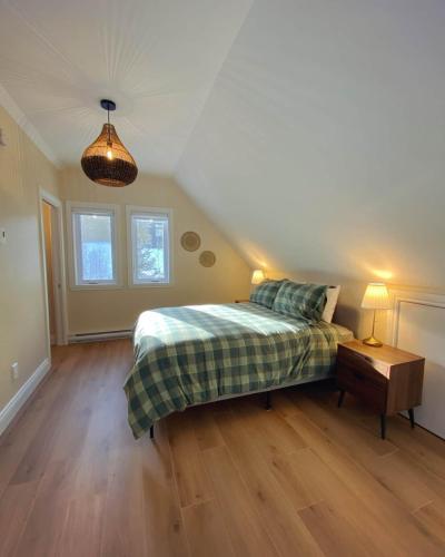 a bedroom with a bed and a wooden floor at La Bellecôte - Relaxation in nature and spa in Petite-Rivière-Saint-François