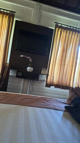 uma pessoa deitada numa cama com uma televisão de ecrã plano em Balangan Surf Resort em Jimbaran