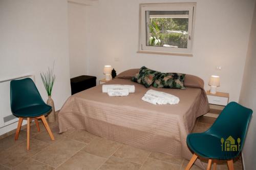 a bedroom with a bed with two green chairs at Villa Tra i Pini - Green & Relax in Castellana Grotte