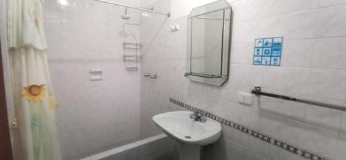een witte badkamer met een wastafel en een spiegel bij El Cumbe Inn in Cajamarca