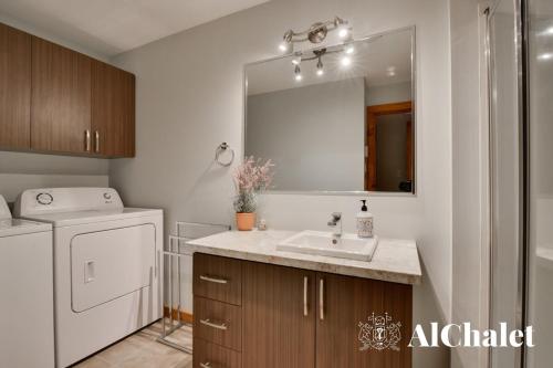 a bathroom with a sink and a washing machine at B-Évasion Chalet avec spa sauna in Petite-Rivière-Saint-François