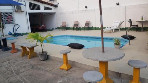 a swimming pool with tables and chairs in a building at Pousada e Hostel sol e mar in João Pessoa