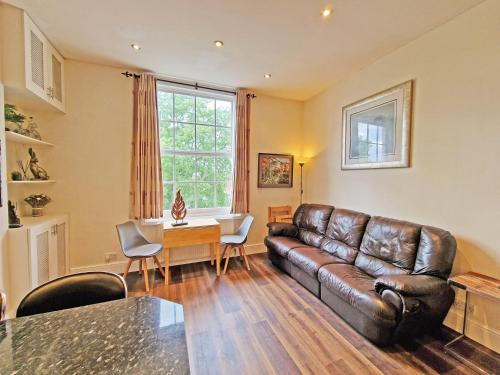 a living room with a leather couch and a table at Canal Side 2 Bedroom Apartment in Leamington Spa