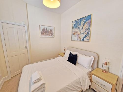 a small bedroom with a white bed and a night stand at Canal Side 2 Bedroom Apartment in Leamington Spa