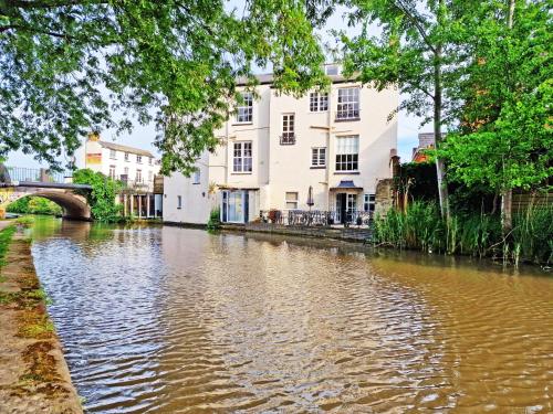 a river in a city with houses and a bridge at Canal Side 2 Bedroom Apartment in Leamington Spa