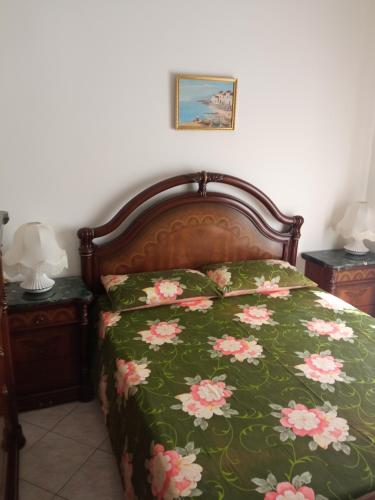 a bed with a green blanket with pink flowers on it at Torre Carlo V in Porto Empedocle