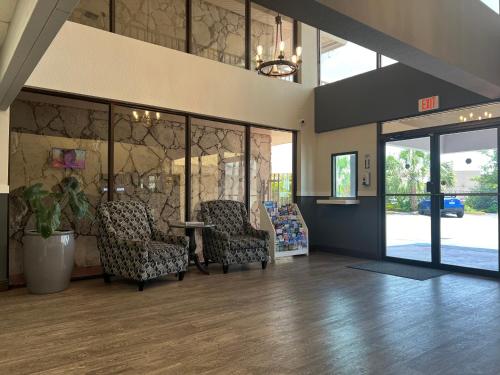 a lobby with two chairs and a table and glass doors at Garden Inn Homestead/Everglades/Gateway to Keys in Homestead