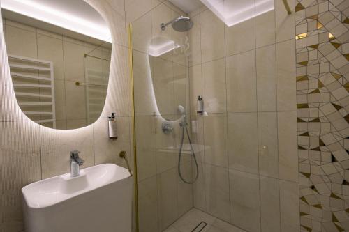 a bathroom with a shower and a sink and a mirror at Boulevard Boutique Suites in Łeba