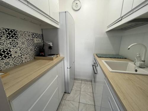 une petite cuisine avec un évier et un réfrigérateur dans l'établissement Appartement T3 rénové avec loggias, à deux pas de la mer et des commerces, parking privé inclus! - FR-1-324A-64, à Saint-Hilaire-de-Riez