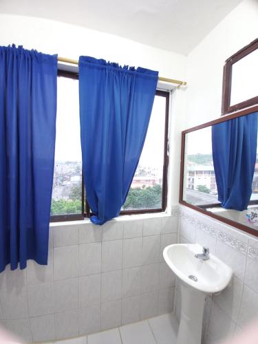 baño con lavabo y cortina azul en MONTANITA Hugos Place, en Montañita