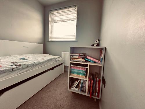 a bedroom with a bed and a book shelf with books at Chic Family Home Near Parks & Leicester Uni in Leicester