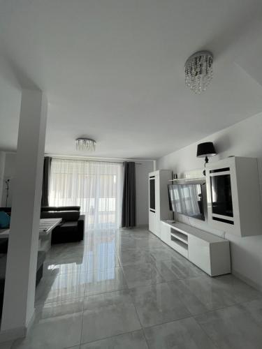 a white living room with a television and a couch at Apartament pod Łebą in Charbrowo