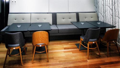 a dining room with two tables and chairs and a couch at Hotel Berthelot in Bucharest