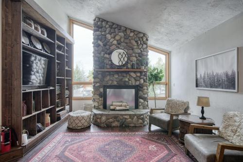 a living room with a stone fireplace with a clock at Wapiti View 6-Bedroom Cabin 28mins to Yellowstone in Island Park