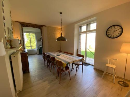 une salle à manger avec une table et une horloge au mur dans l'établissement Maison LéoCha, à Sablons-sur-Huisne