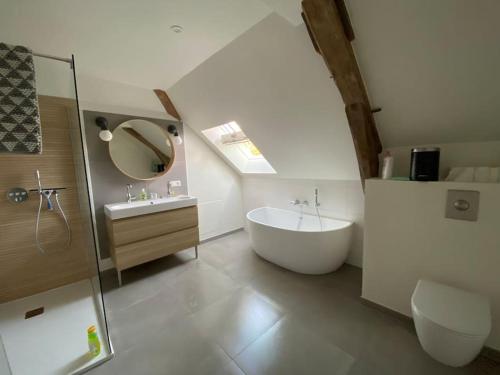 une salle de bain avec une baignoire, un lavabo et un miroir dans l'établissement Maison LéoCha, à Sablons-sur-Huisne