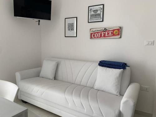 a white couch in a living room with a coffee sign at Salentipity in Marina di Pescoluse