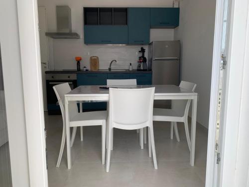 a kitchen with a white table and white chairs at Salentipity in Marina di Pescoluse