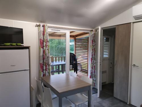 un pequeño comedor con mesa y ventana en Mobilhome climatisé 3 chambres 6 pers cosy au vert en bordure de l'Eure JO2024, en Ivry-la-Bataille