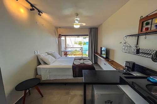 um quarto de hotel com uma cama e uma cozinha em Casa Varandas - Estúdio Budião (Tv+Frigobar+A/C) em Ubatuba