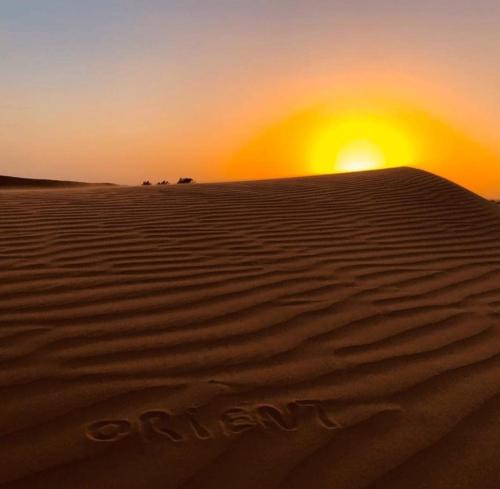 Una puesta de sol en el desierto con la puesta del sol en ORIENT CAMP, en Sidi Kasem Zemmal