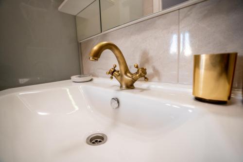 a sink with a gold faucet and a mirror at Palomino house in Sinj