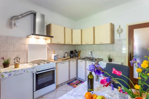 a kitchen with white appliances and a table with flowers at House Gioia Cristina in Labin