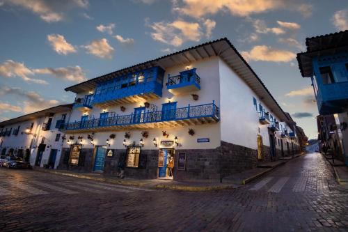 a white building with blue windows on a street at Hotel Hacienda Cusco Plaza in Cusco