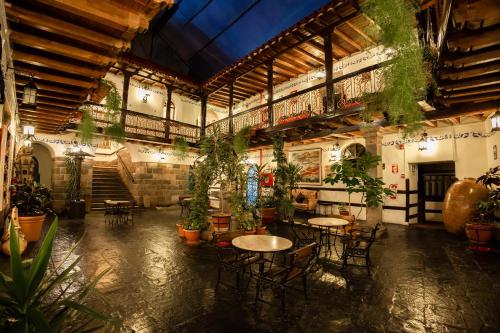 a room with tables and chairs and potted plants at Hotel Hacienda Cusco Plaza in Cusco