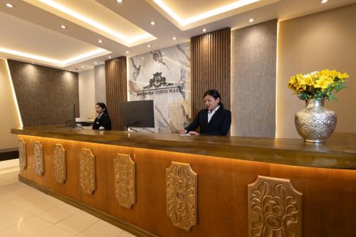 two people sitting at a reception desk at Hotel Hacienda Cusco Plaza in Cusco